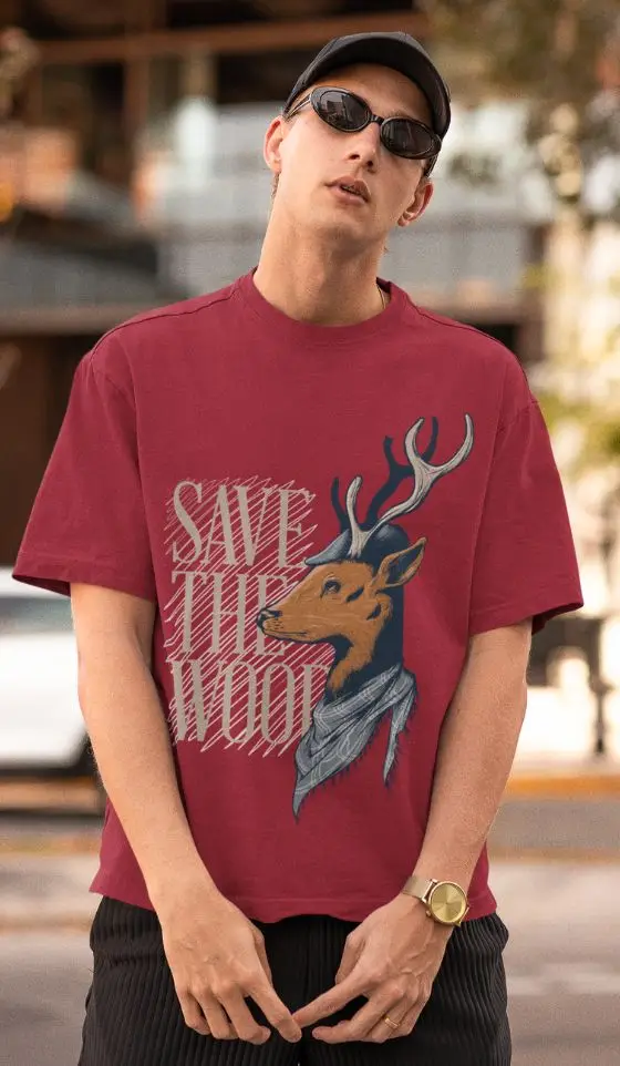 Model wearing a Maroon oversized graphic t-shirt with 'Save The Wood' deer print, styled with sunglasses and a cap.