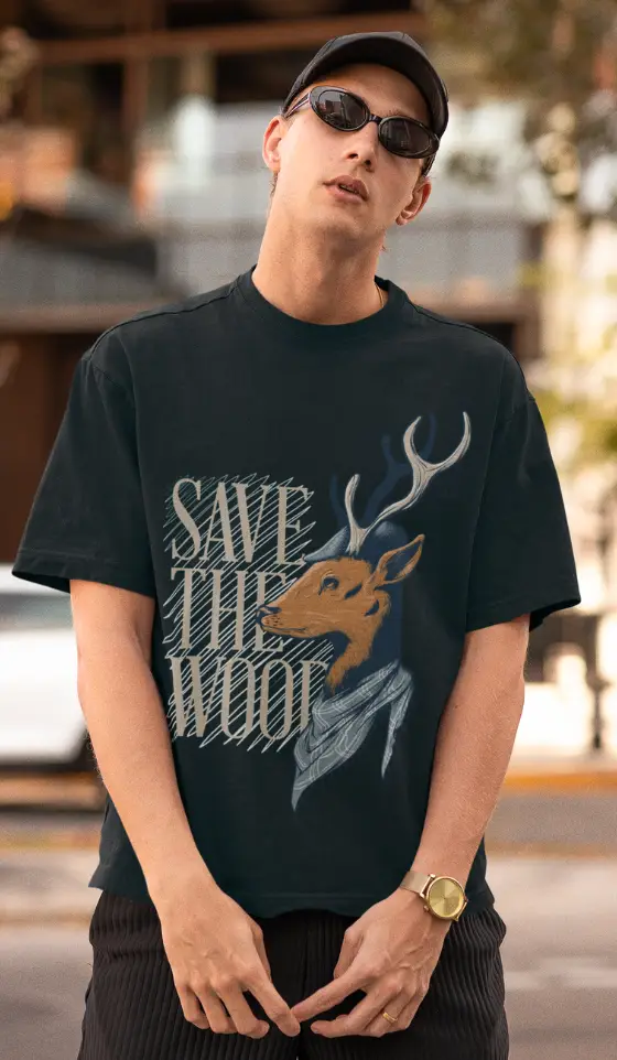 Model wearing a Petrol Blue oversized graphic t-shirt with 'Save The Wood' deer print, styled with sunglasses and a cap.